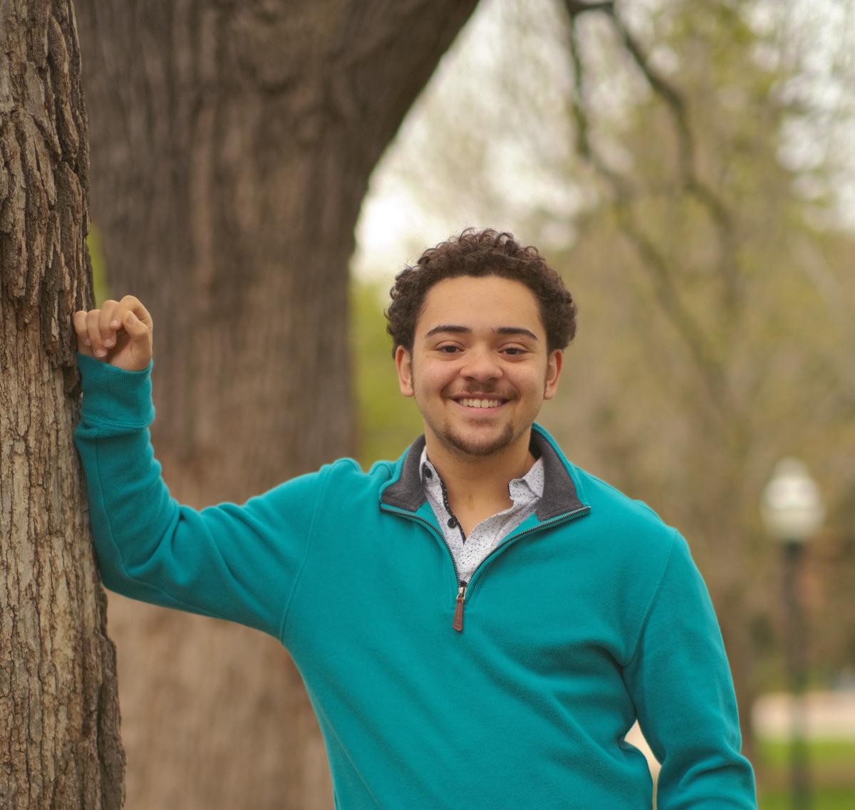 Cameron Borner smiles and leans against a tree.